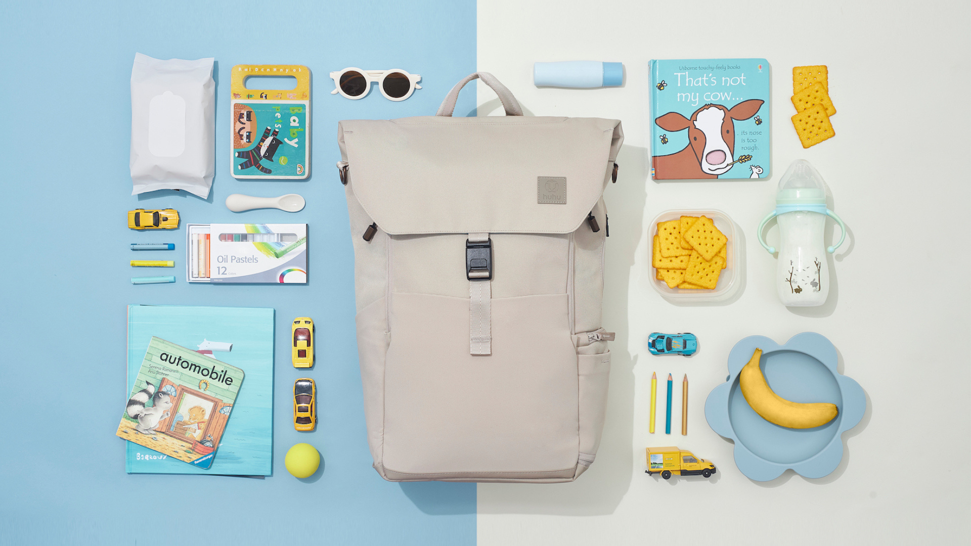 Taupe backpack laid on blue and off-white background. Blue, yellow, and white baby items laid out neatly around backpack.